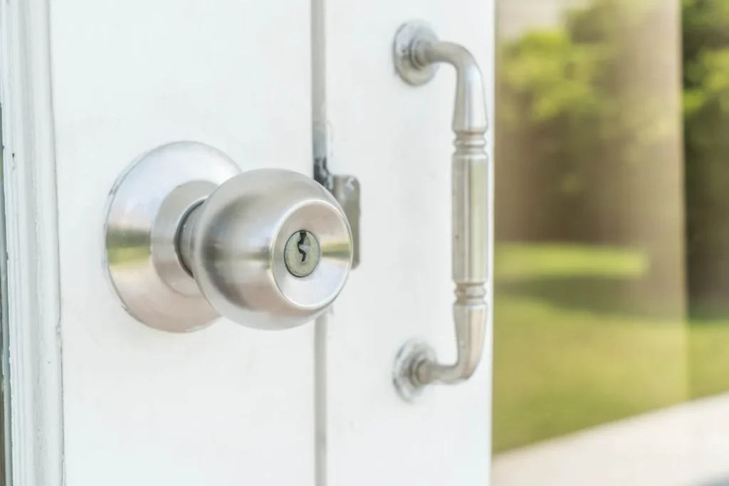 Manija de puerta de acero inoxidable con cerradura en una puerta blanca, mostrando un diseño moderno y elegante.